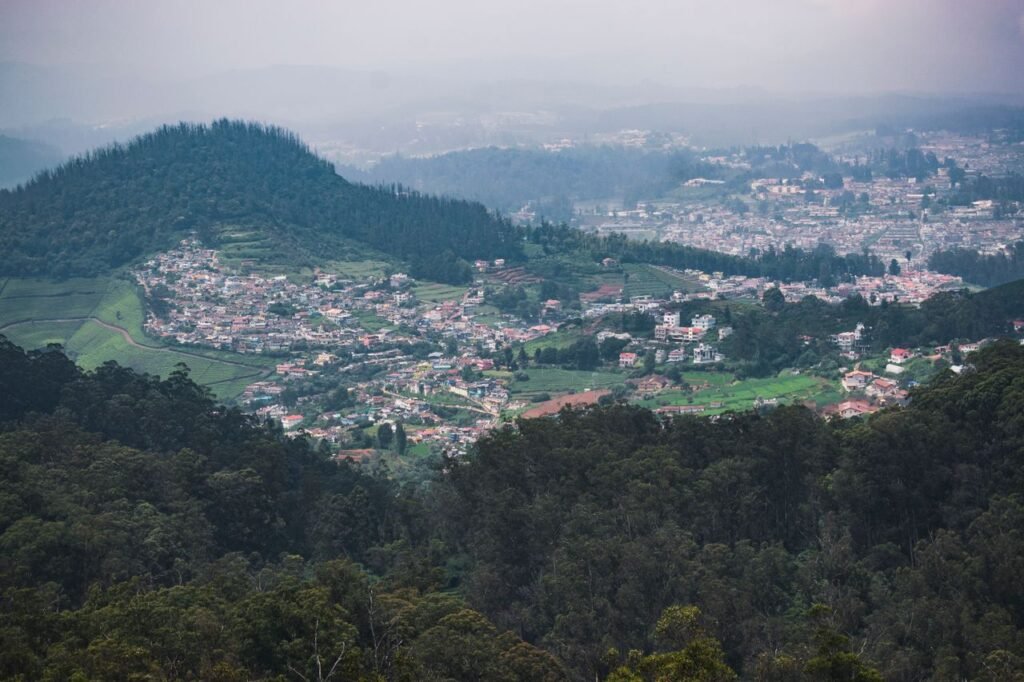 Aerial view of lush Ooty hills and townscape surrounded by verdant forests.